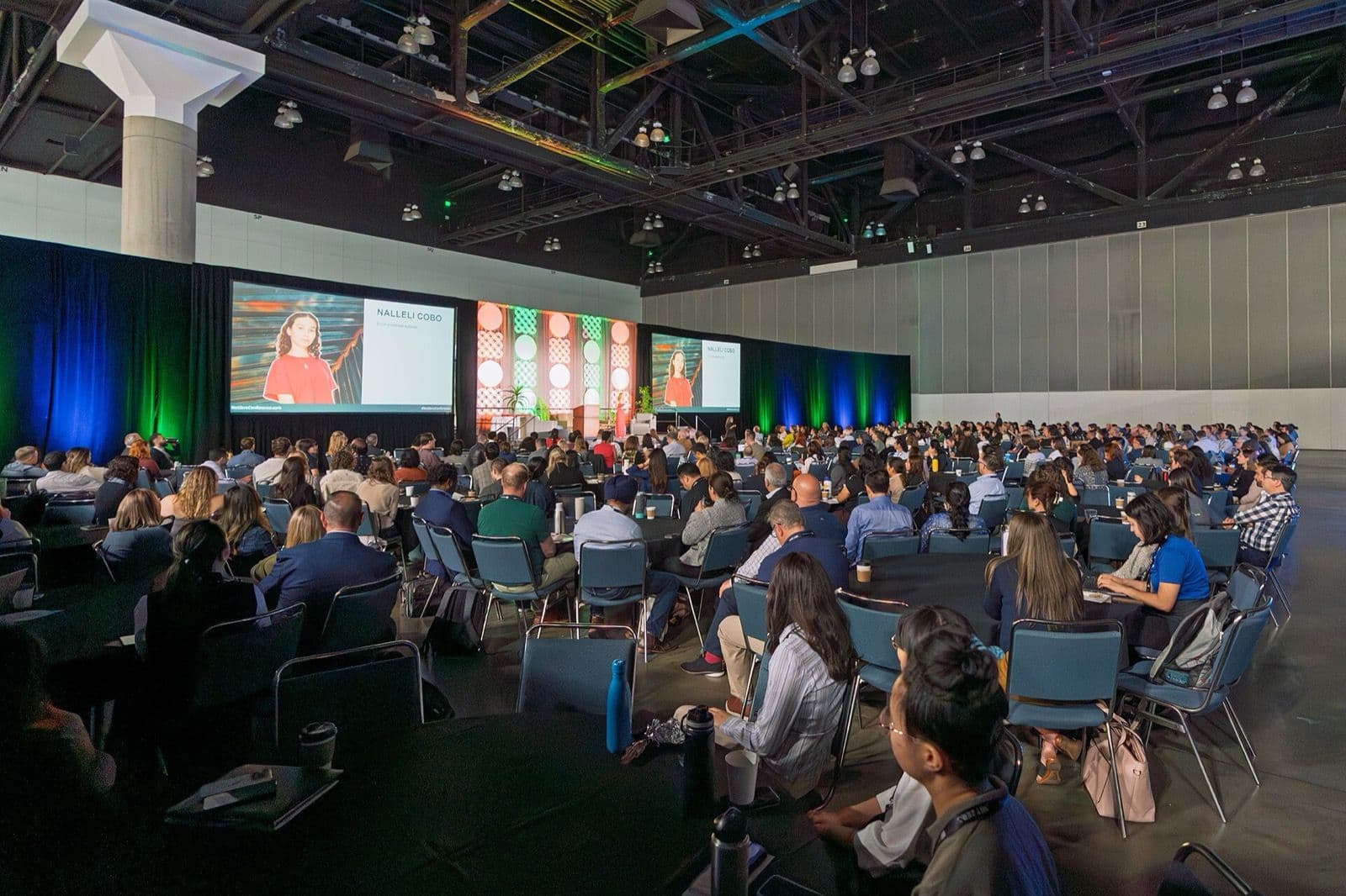 A speaker on stage addressing a full conference hall